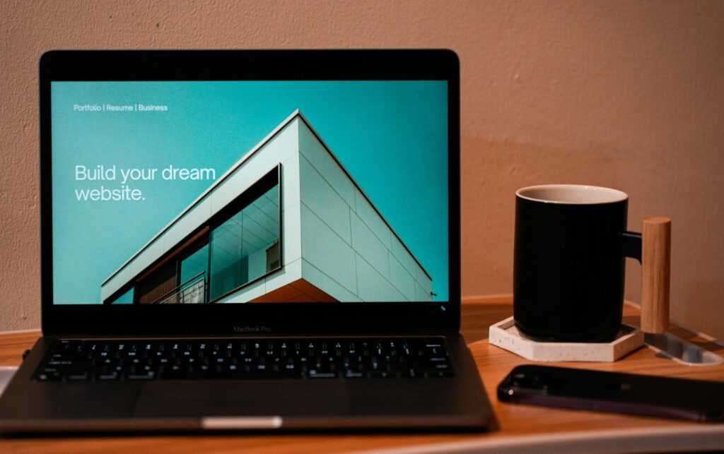Notebook aberto sobre mesa de madeira ao lado de uma xícara, representando a criação de um site